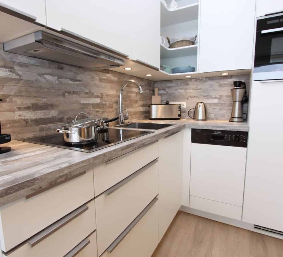 Moderne Einbauküche mit Geschirrspüler ist in das Wohnzimmer integriert und mit hochwertigem Inventar versehen.