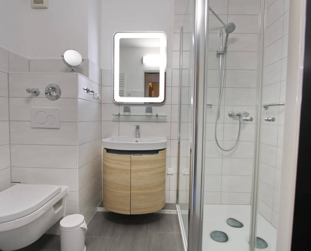 Ein modernes Badezimmer ist mit einem Handtuchheizkörper, einem Waschtisch mit Stauraum für Ihre Kosmetika und Spiegelschrank ausgestattet.