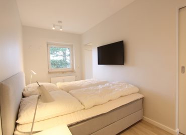 Das Schlafzimmer ist mit einem Boxspringbett (180 x 200 cm), einem Kleiderschrank und einem wandhängenden TV ausgestattet.